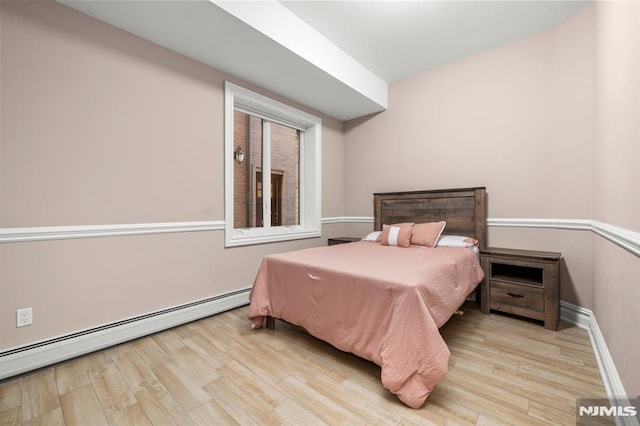 bedroom featuring a baseboard heating unit and light wood-type flooring