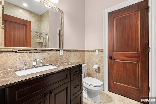 bathroom with tile patterned flooring, tile walls, a shower with shower door, toilet, and vanity