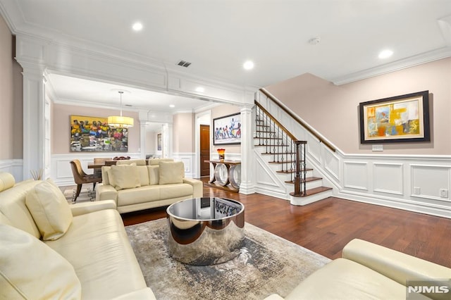 living room featuring decorative columns, crown molding, and hardwood / wood-style flooring