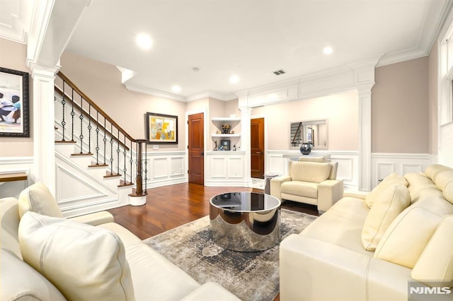 living room featuring ornate columns, wood-type flooring, built in shelves, and crown molding