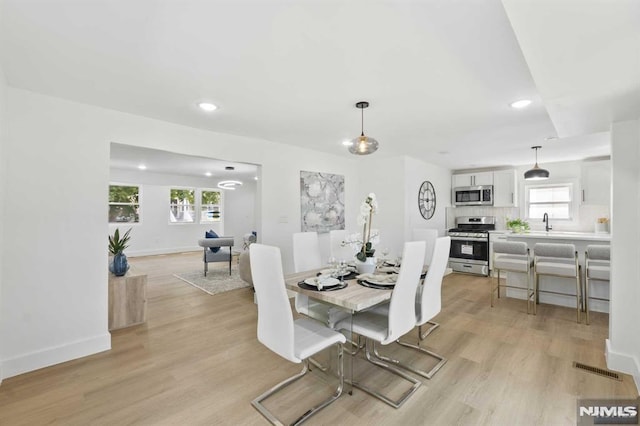 dining area with light wood-type flooring, plenty of natural light, and sink