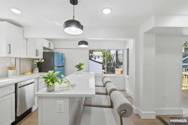 kitchen with a kitchen bar, appliances with stainless steel finishes, backsplash, pendant lighting, and white cabinets