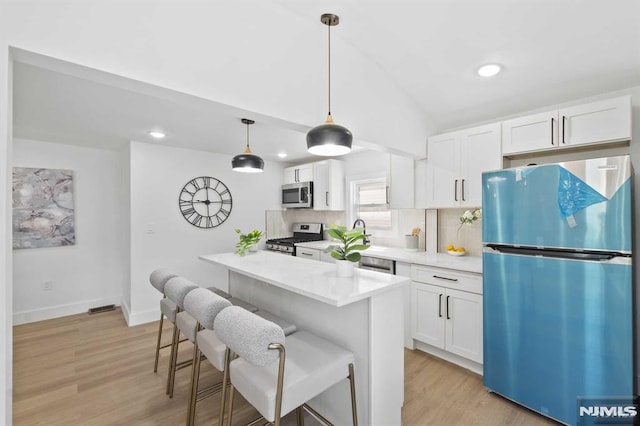 kitchen featuring white cabinets, decorative backsplash, stainless steel appliances, and decorative light fixtures