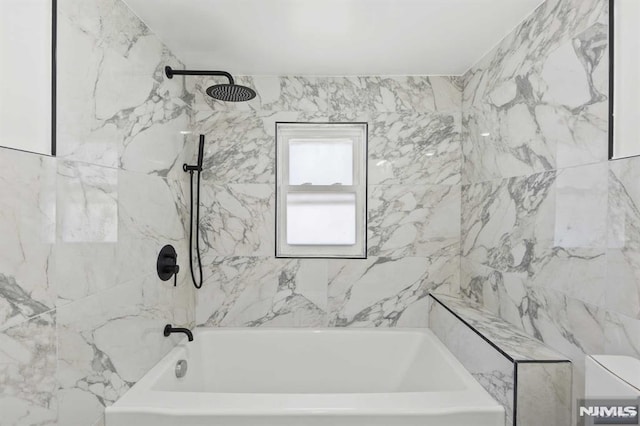 bathroom with tiled shower / bath combo and toilet