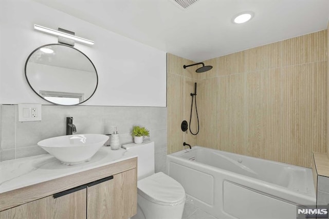 full bathroom with shower / tub combination, vanity, tile walls, and toilet