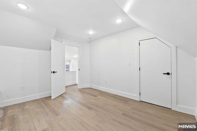 additional living space with light hardwood / wood-style flooring and lofted ceiling