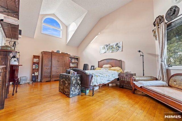 bedroom with light wood-type flooring and high vaulted ceiling