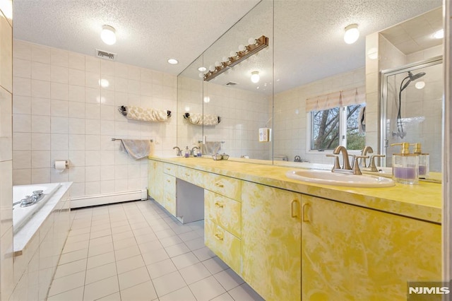 bathroom with a textured ceiling, baseboard heating, tile patterned floors, plus walk in shower, and vanity