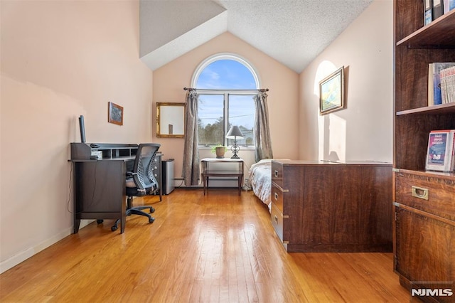 bedroom featuring lofted ceiling, a textured ceiling, and light wood-type flooring