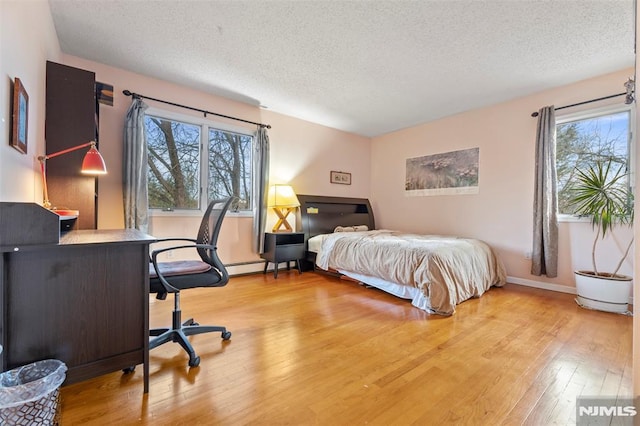 bedroom featuring a textured ceiling, multiple windows, and light hardwood / wood-style floors