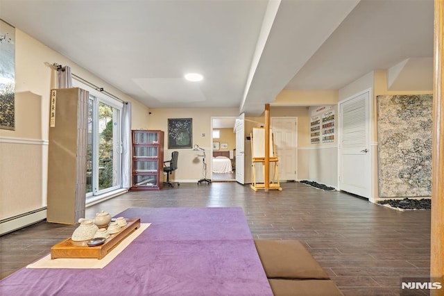 exercise room with dark hardwood / wood-style flooring and baseboard heating