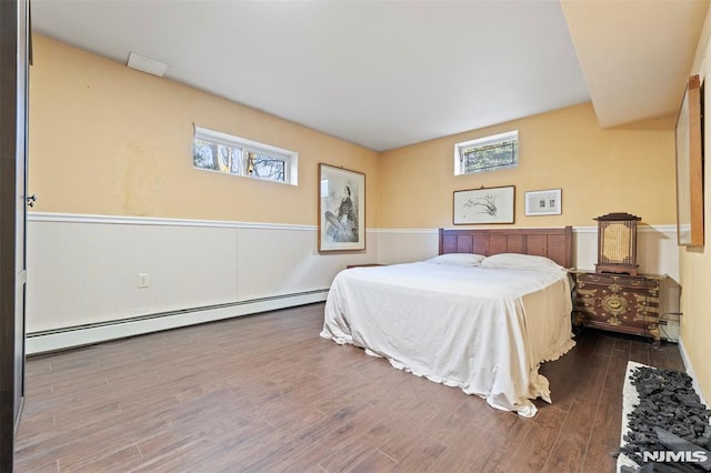 bedroom with dark hardwood / wood-style flooring and a baseboard heating unit