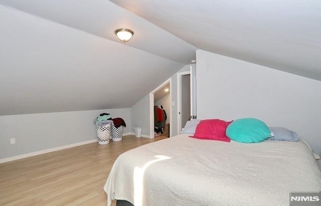 bedroom featuring lofted ceiling and light wood-type flooring