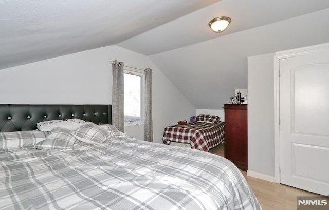 bedroom featuring light wood-type flooring and lofted ceiling