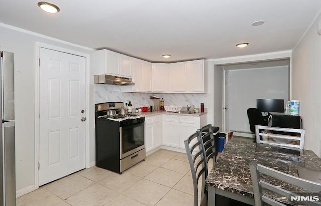 kitchen featuring white cabinetry, stainless steel appliances, ventilation hood, backsplash, and light tile patterned floors