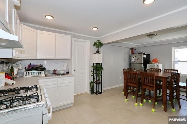 kitchen featuring decorative backsplash, white appliances, ventilation hood, sink, and white cabinetry