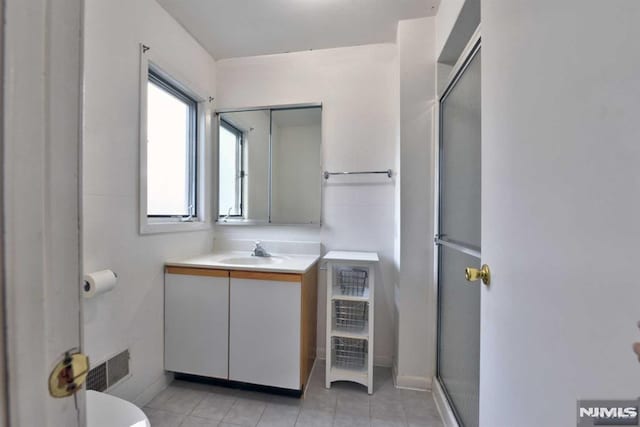 bathroom featuring toilet, vanity, tile patterned floors, and walk in shower