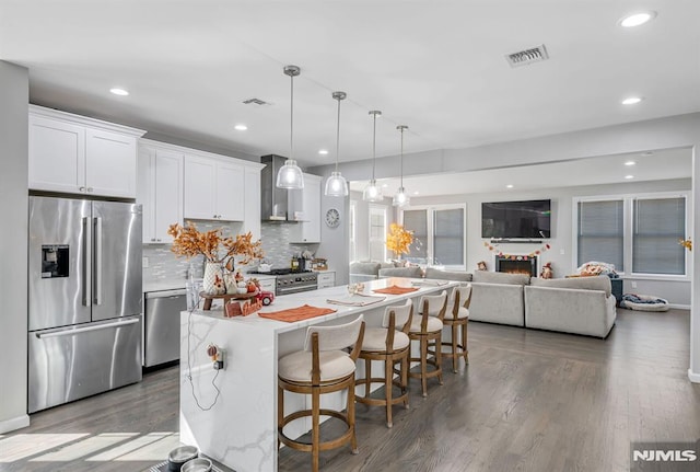 kitchen featuring a center island, white cabinets, hanging light fixtures, appliances with stainless steel finishes, and a kitchen bar