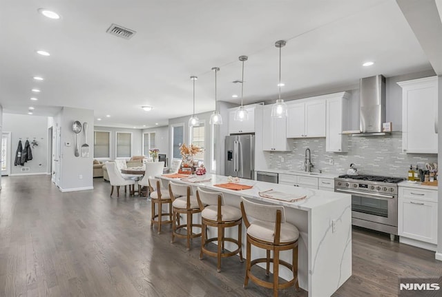 kitchen featuring white cabinetry, sink, wall chimney range hood, a kitchen island, and high end appliances