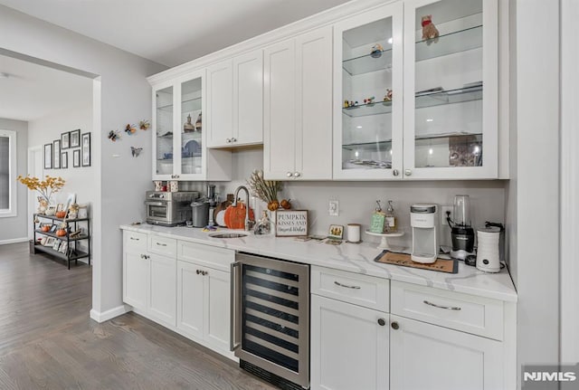 bar featuring white cabinetry, sink, beverage cooler, and light stone counters