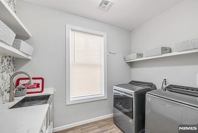 washroom featuring separate washer and dryer, sink, cabinets, and hardwood / wood-style flooring