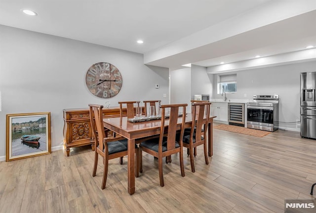 dining room featuring wine cooler, light hardwood / wood-style flooring, and sink