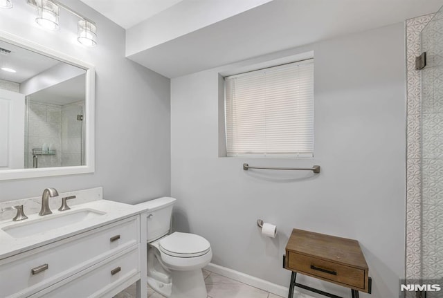 bathroom with tile patterned floors, vanity, toilet, and tiled shower