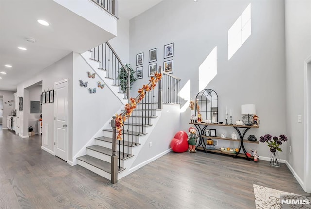 stairway with a high ceiling and hardwood / wood-style flooring