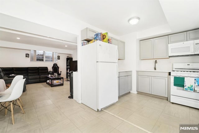 kitchen featuring white appliances, gray cabinets, and sink