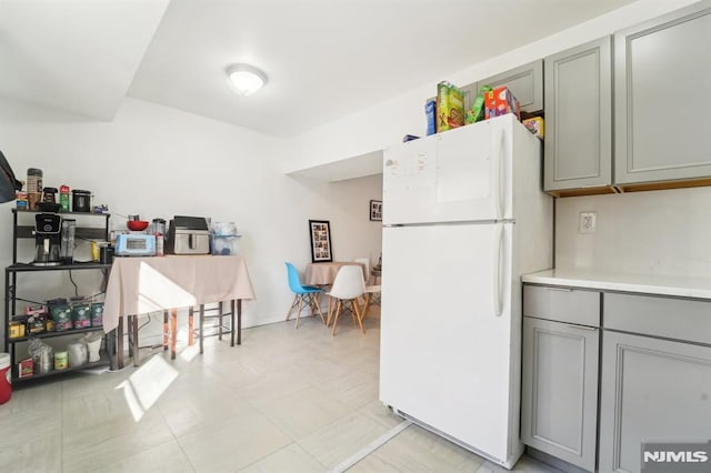 kitchen featuring gray cabinets and white fridge