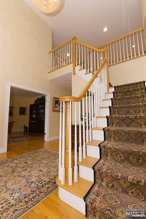 stairway with a towering ceiling and wood-type flooring