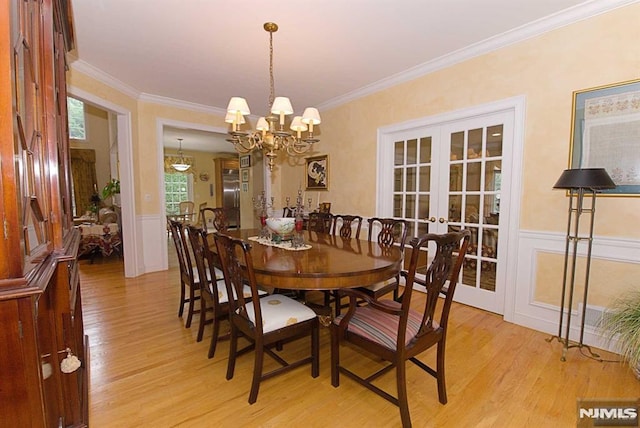 dining room featuring french doors, crown molding, light hardwood / wood-style floors, and a notable chandelier