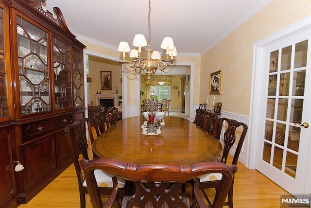 dining space with a chandelier, ornamental molding, and light hardwood / wood-style flooring