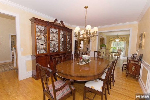 dining area with an inviting chandelier, ornamental molding, and light hardwood / wood-style floors