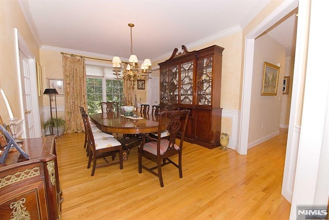 dining space with light hardwood / wood-style flooring, an inviting chandelier, and crown molding