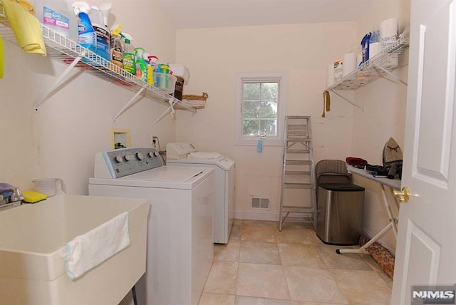 clothes washing area with washer and dryer, sink, and light tile patterned floors