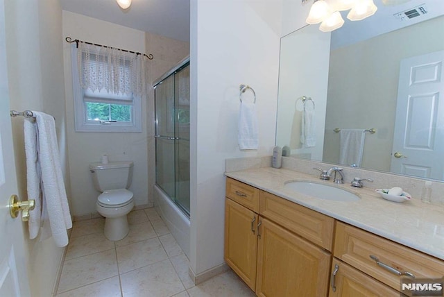 full bathroom with tile patterned flooring, bath / shower combo with glass door, vanity, and toilet