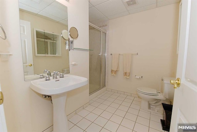 bathroom featuring toilet, a drop ceiling, tile patterned floors, and a shower with shower door