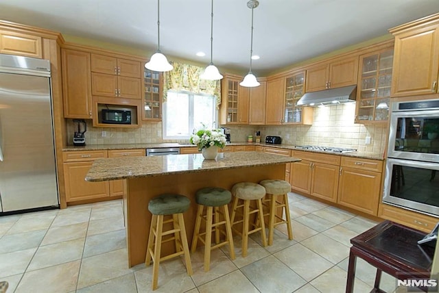 kitchen featuring light stone countertops, built in appliances, pendant lighting, and a kitchen island