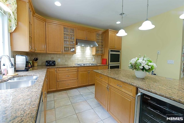 kitchen with sink, stainless steel appliances, tasteful backsplash, beverage cooler, and hanging light fixtures