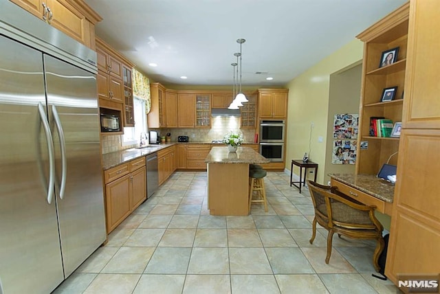 kitchen featuring light stone countertops, pendant lighting, a center island, a kitchen bar, and appliances with stainless steel finishes