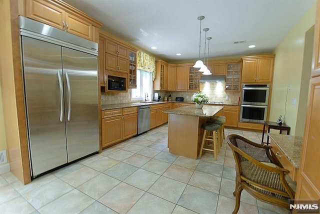 kitchen featuring built in appliances, light stone countertops, exhaust hood, and a center island