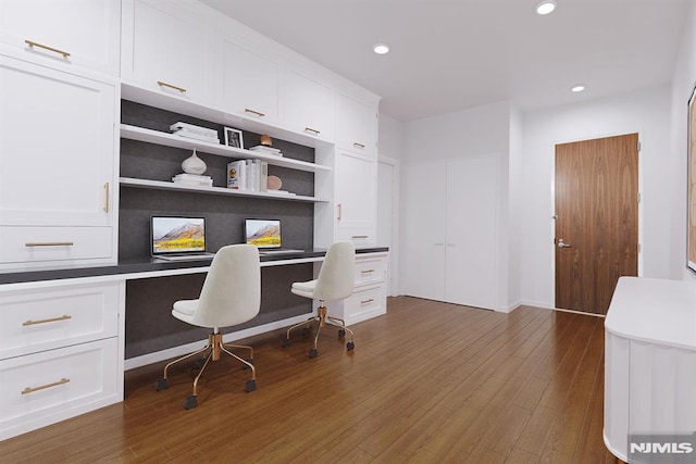 home office featuring built in features, dark hardwood / wood-style flooring, and built in desk