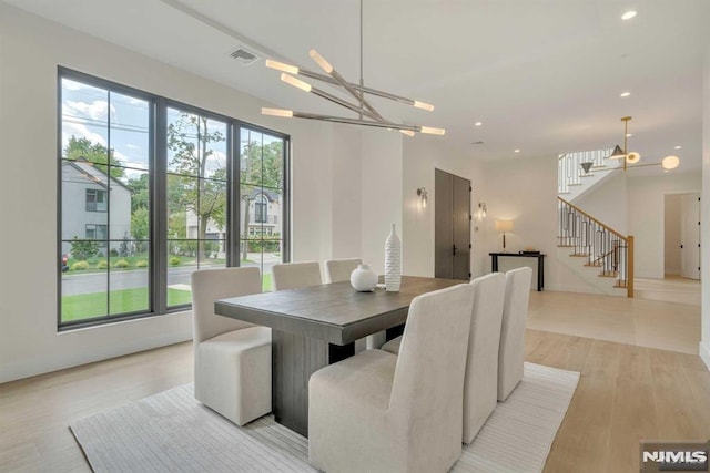 dining space with light wood-type flooring and a notable chandelier