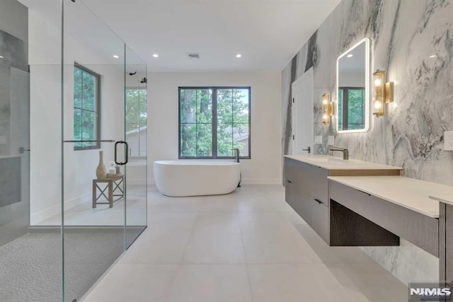 bathroom with shower with separate bathtub, vanity, tile patterned floors, and tile walls