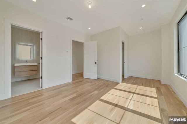 unfurnished bedroom featuring light wood-type flooring and connected bathroom