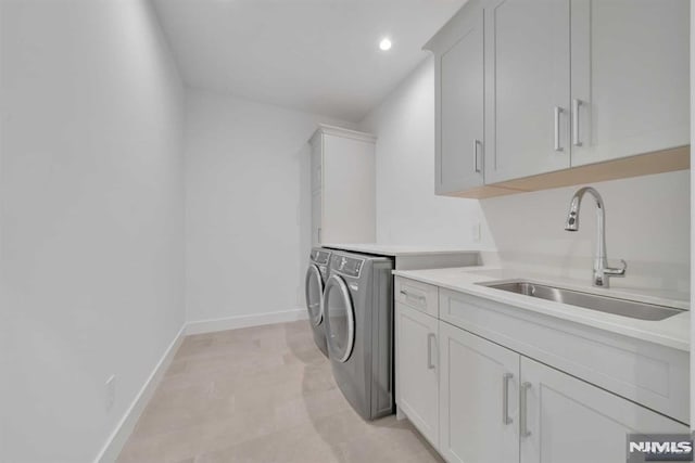 washroom with washer and clothes dryer, cabinets, and sink