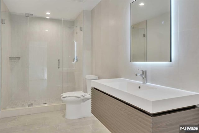 bathroom featuring tile patterned floors, vanity, toilet, and walk in shower