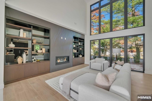 living room featuring wood-type flooring, a towering ceiling, and a fireplace