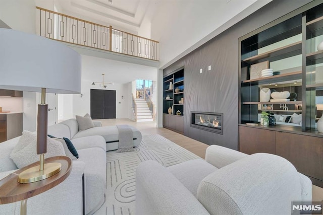 living room featuring built in shelves, a fireplace, and a towering ceiling